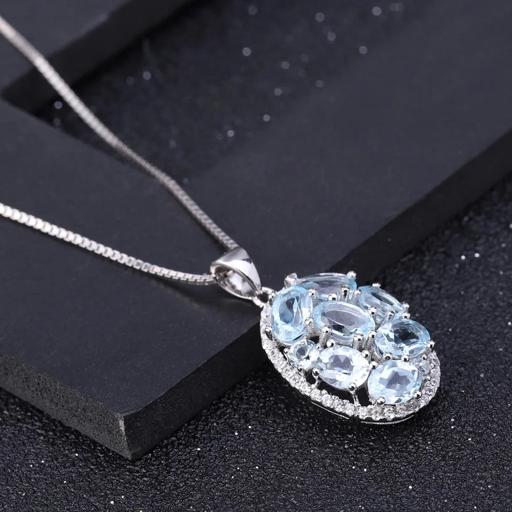 Oval silver pendant with light blue gemstones and surrounding crystal accents