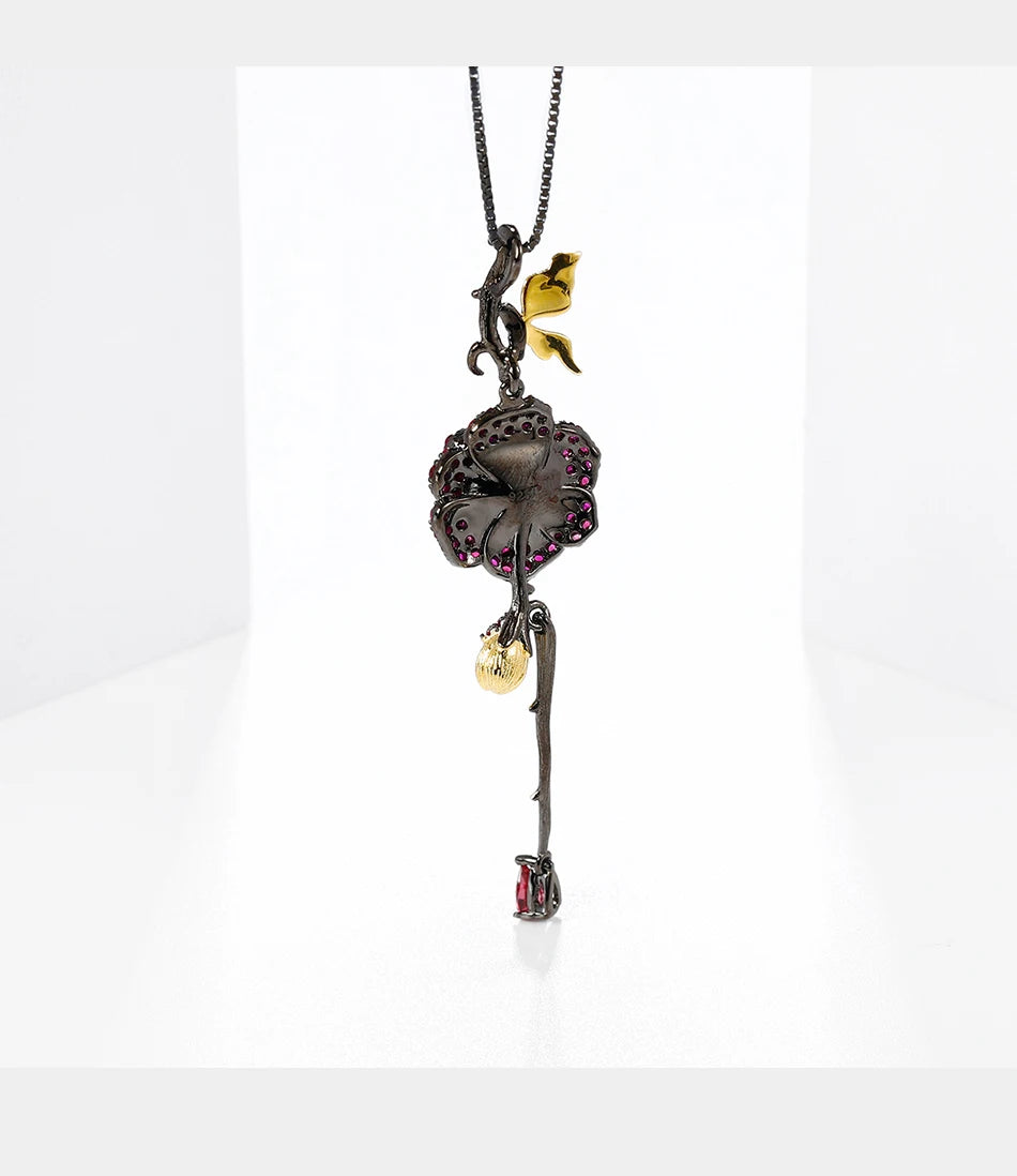 Pendant necklace with a dark rose-shaped bloom in ruby stones, accented by golden leaves and a delicate drop, from the Rossa Collection.