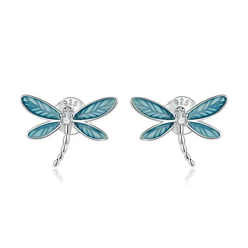 Silver dragonfly stud earrings with translucent blue enamel wings and a tiny clear gemstone on the body