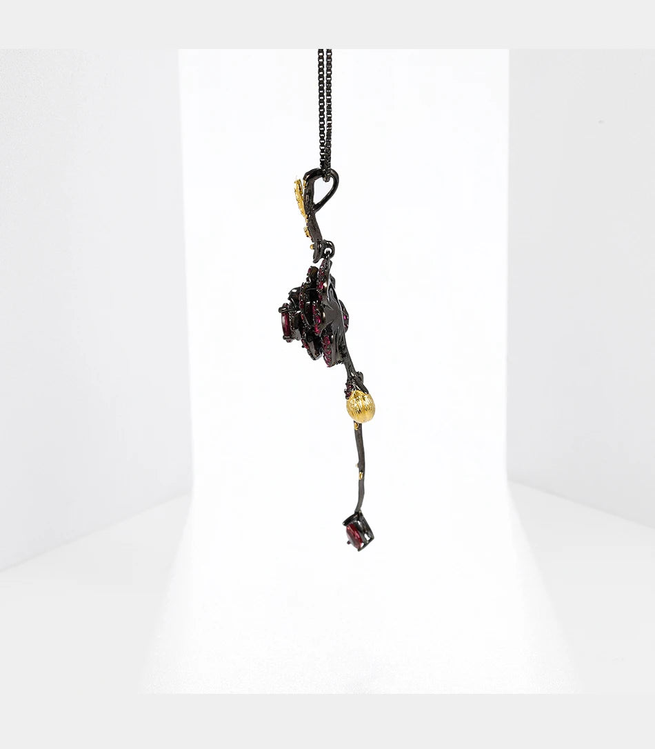 Pendant necklace with a dark rose-shaped bloom in ruby stones, accented by golden leaves and a delicate drop, from the Rossa Collection.
