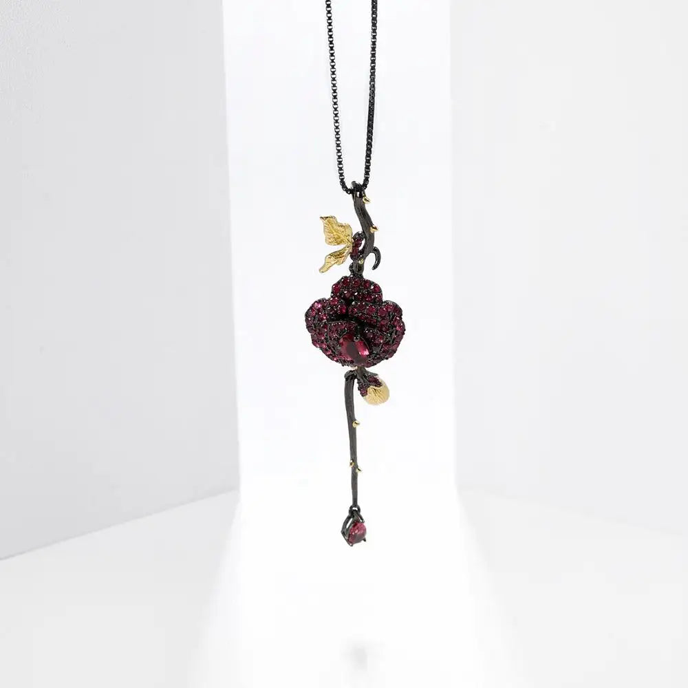 Pendant necklace with a dark rose-shaped bloom in ruby stones, accented by golden leaves and a delicate drop, from the Rossa Collection.