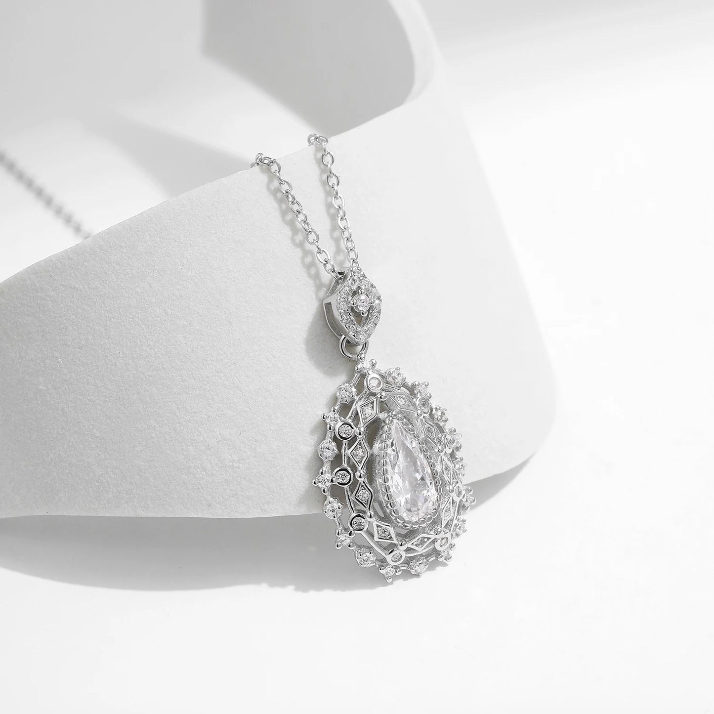 Ornate silver necklace with an intricate teardrop pendant, featuring a central pear-cut white gemstone, part of the Bianco Nero collection.