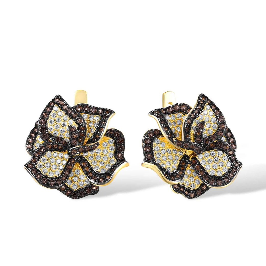 Gold earrings shaped like trillium flowers, paved with white and brown gemstones.