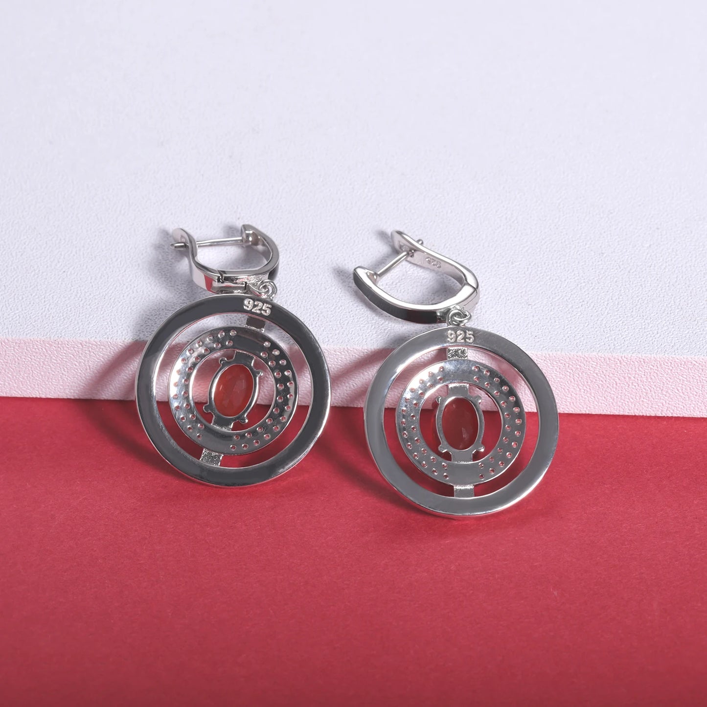 Sterling silver earrings with black enamel rings, pavé-set stones, and central red oval gems, from the Obliqua design.