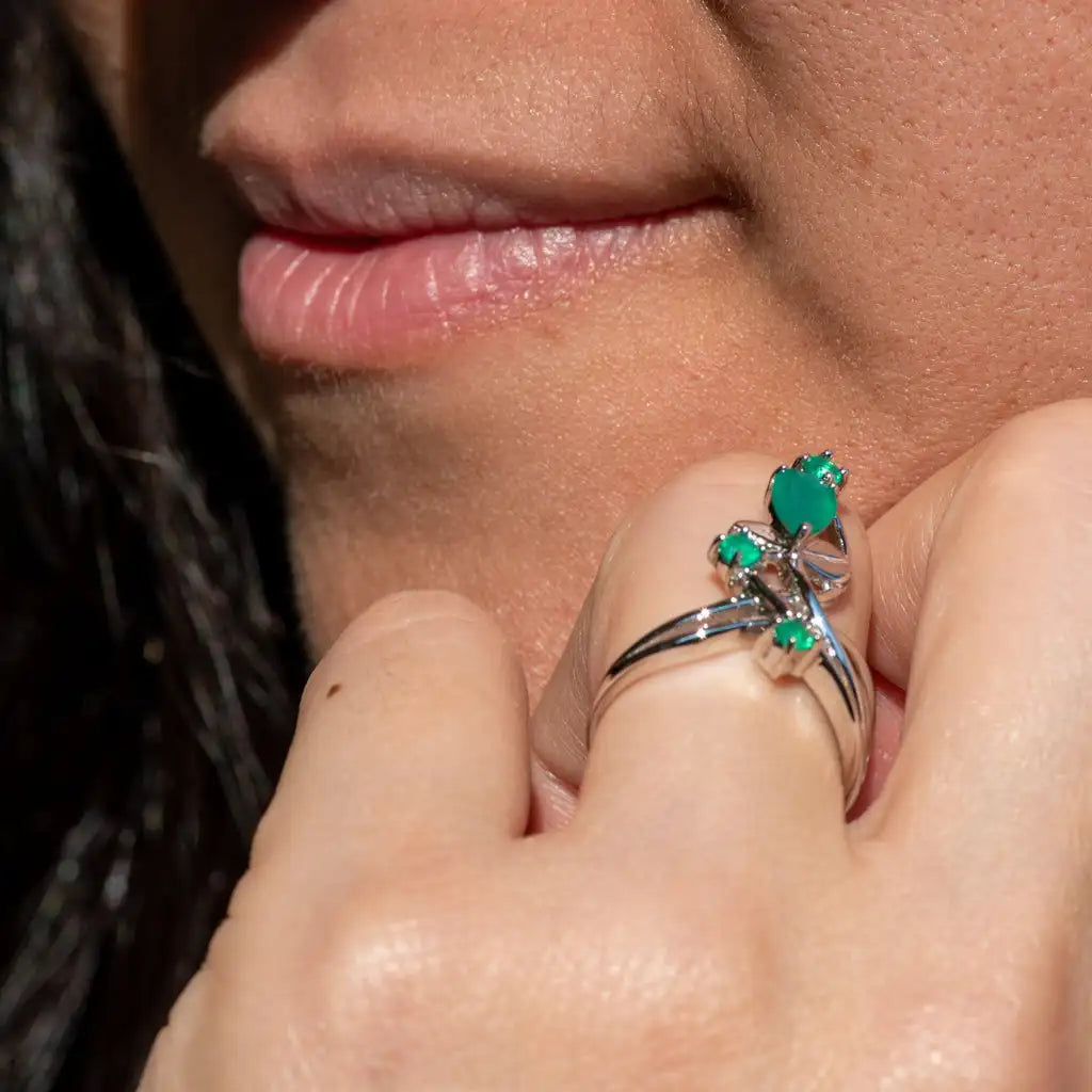 Open silver ring with four green stones arranged like petals on curved stems