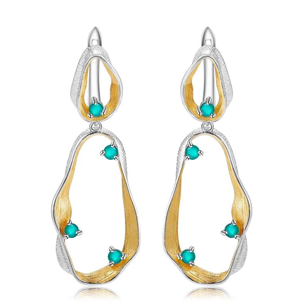 Dangling earrings with flowing gold and silver forms set with turquoise-colored stones