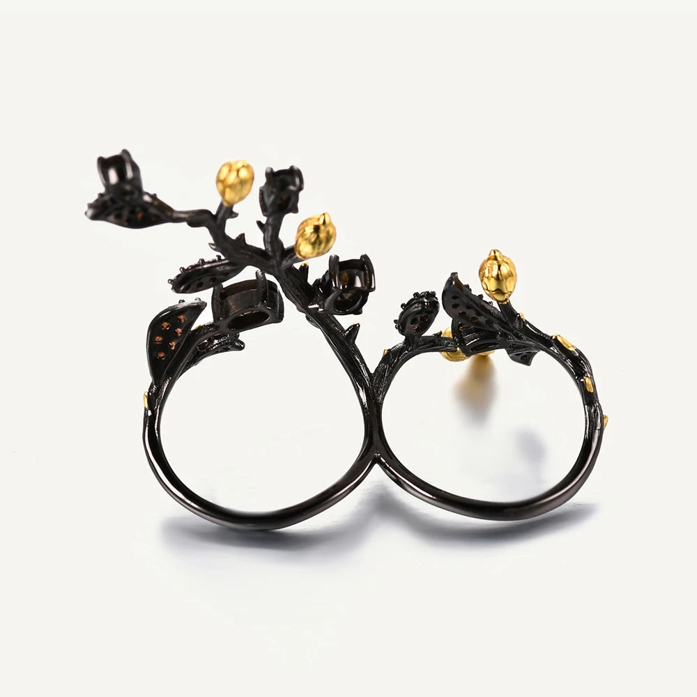 Double-finger black ring shaped like a flowering branch with purple, green, and gold detailing