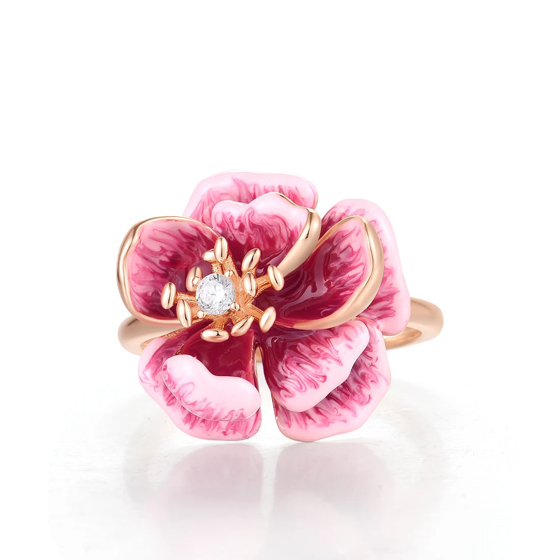 Pink and burgundy enamel flower ring with a central clear gemstone on a gold-tone band.