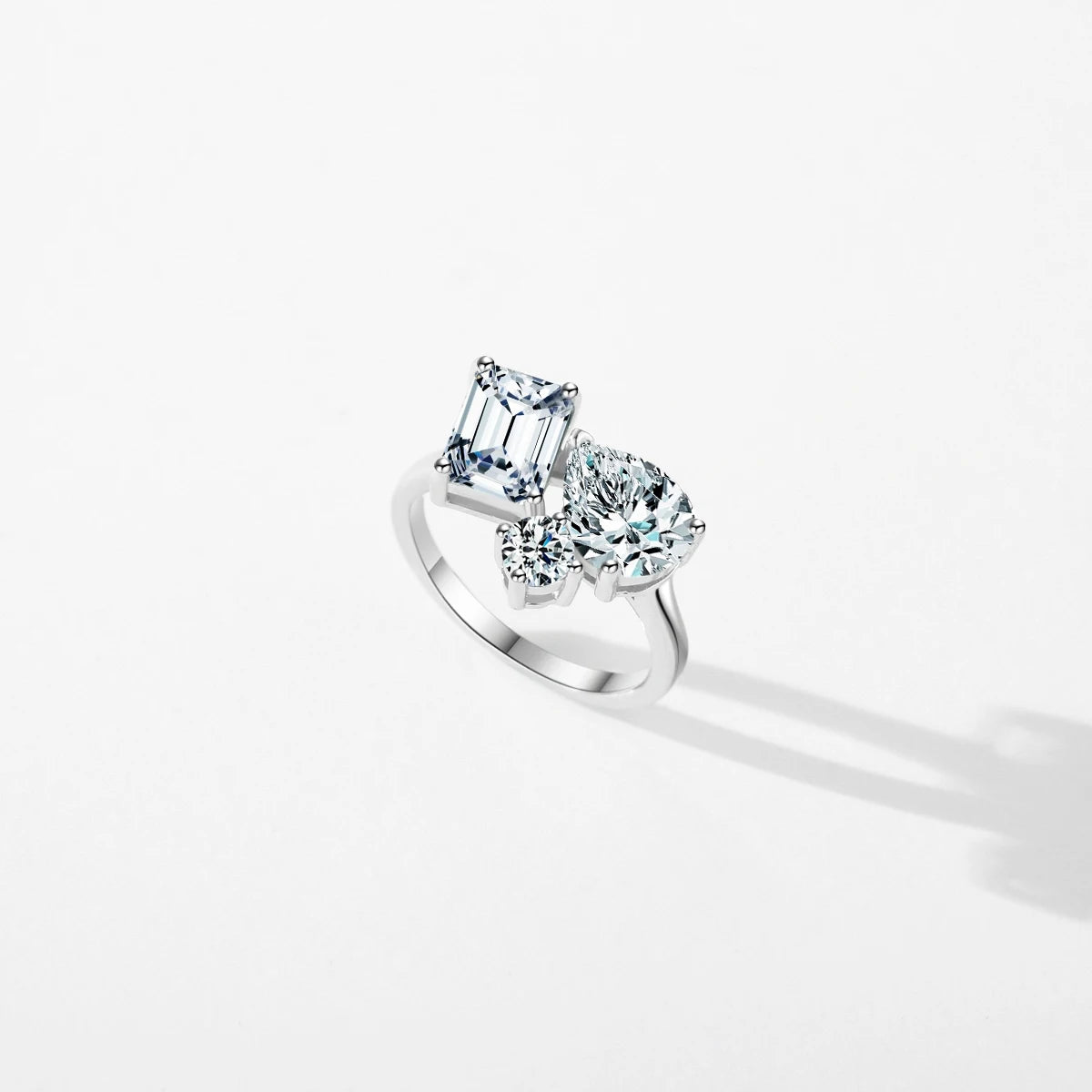Silver ring with a mix of emerald, pear, and round-cut clear stones in an asymmetrical setting