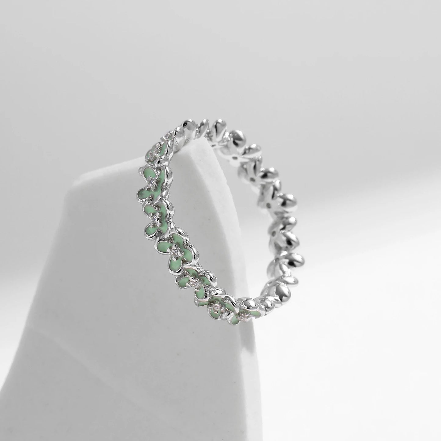 Sterling silver floral band ring with light green enamel petals and tiny diamond accents.
