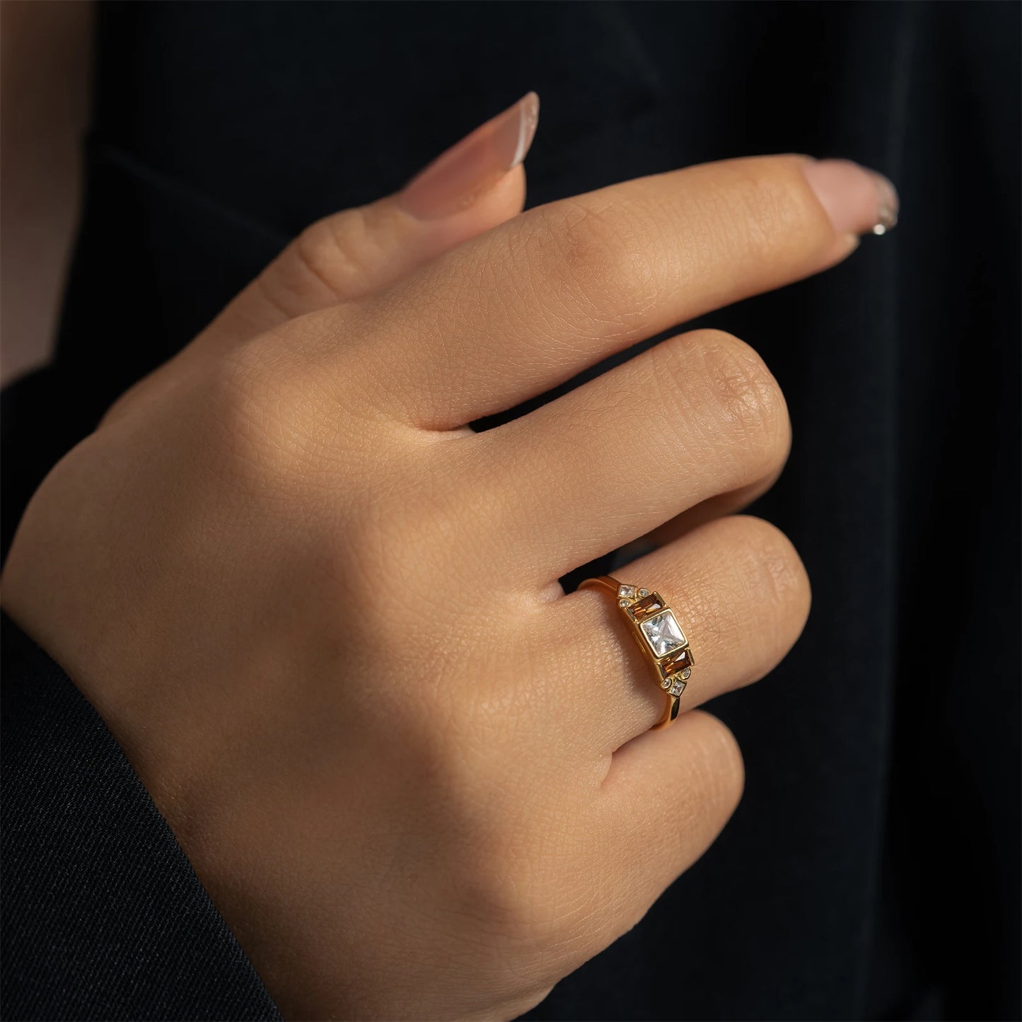 Gold ring with central white stone flanked by smoky square-cut stones and small accent gems