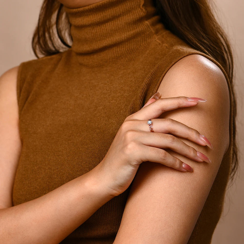 Gold ring with a braided band design and a round-cut clear central stone in a four-prong setting.