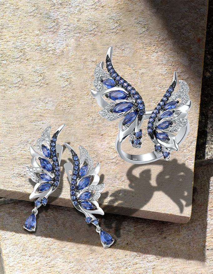 Matching silver ring and earrings set shaped like angel wings with blue and white stones in layered design