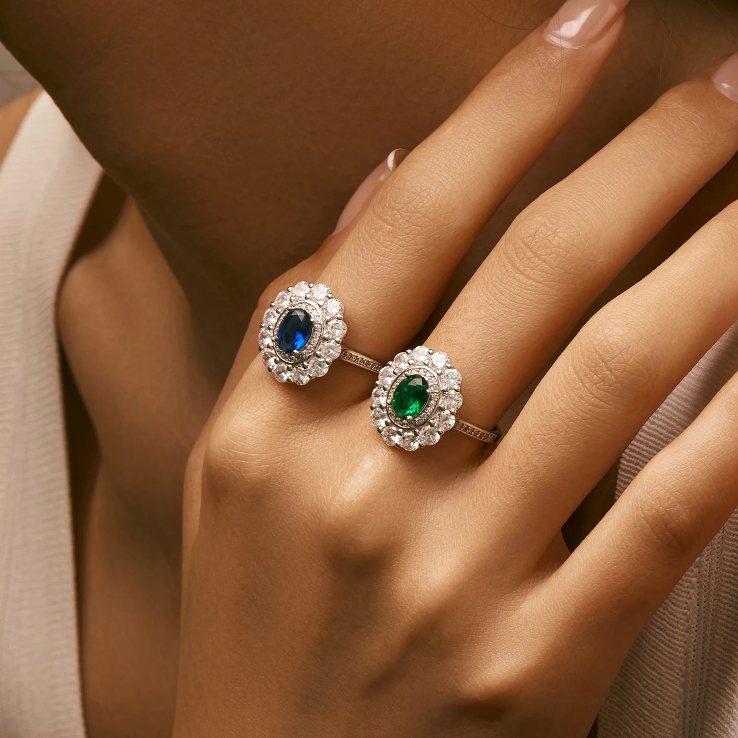 Silver ring with an oval deep blue or green stone surrounded by two halos of clear zirconia stones
