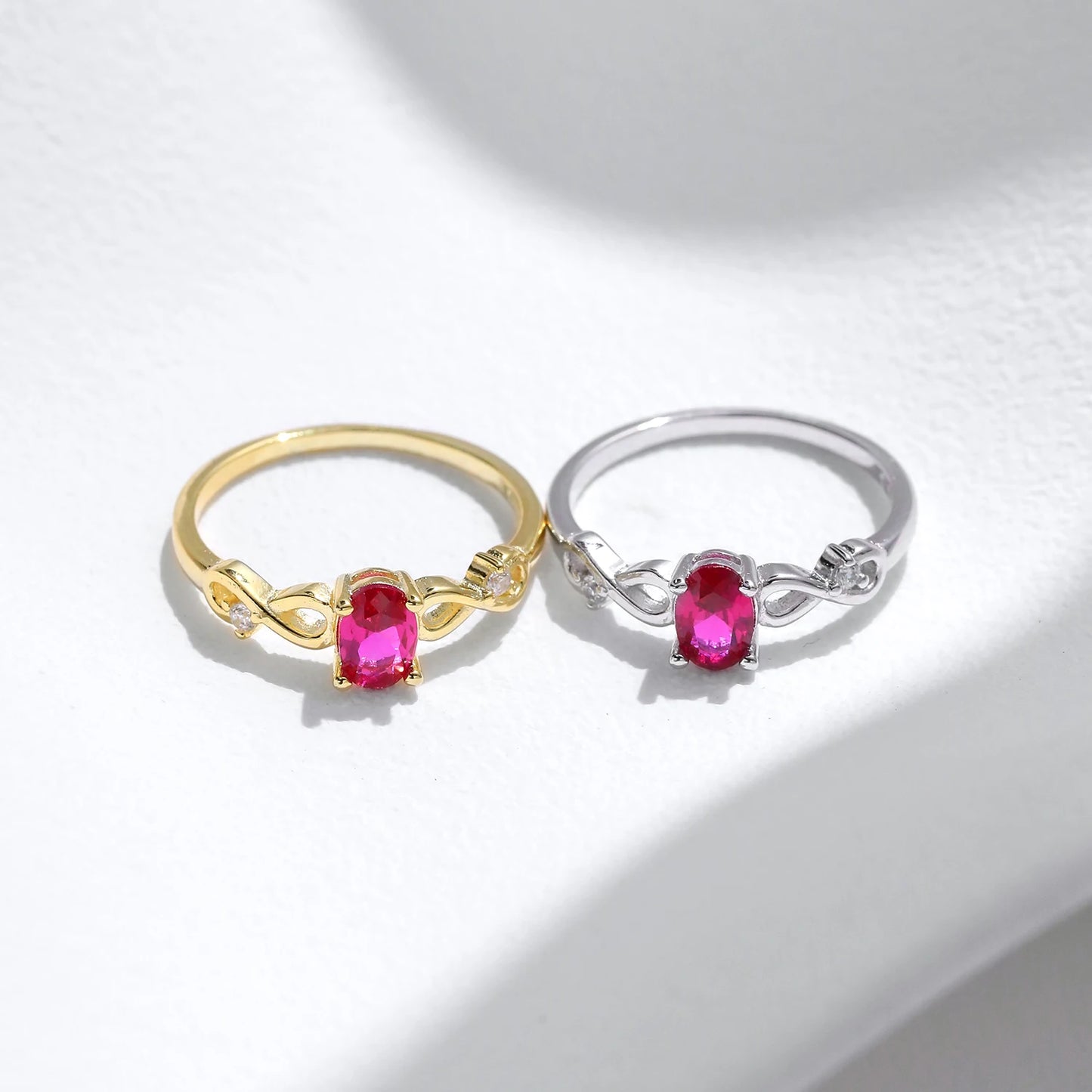 Gold-plated ring with an oval pink gemstone and twisted infinity-style band