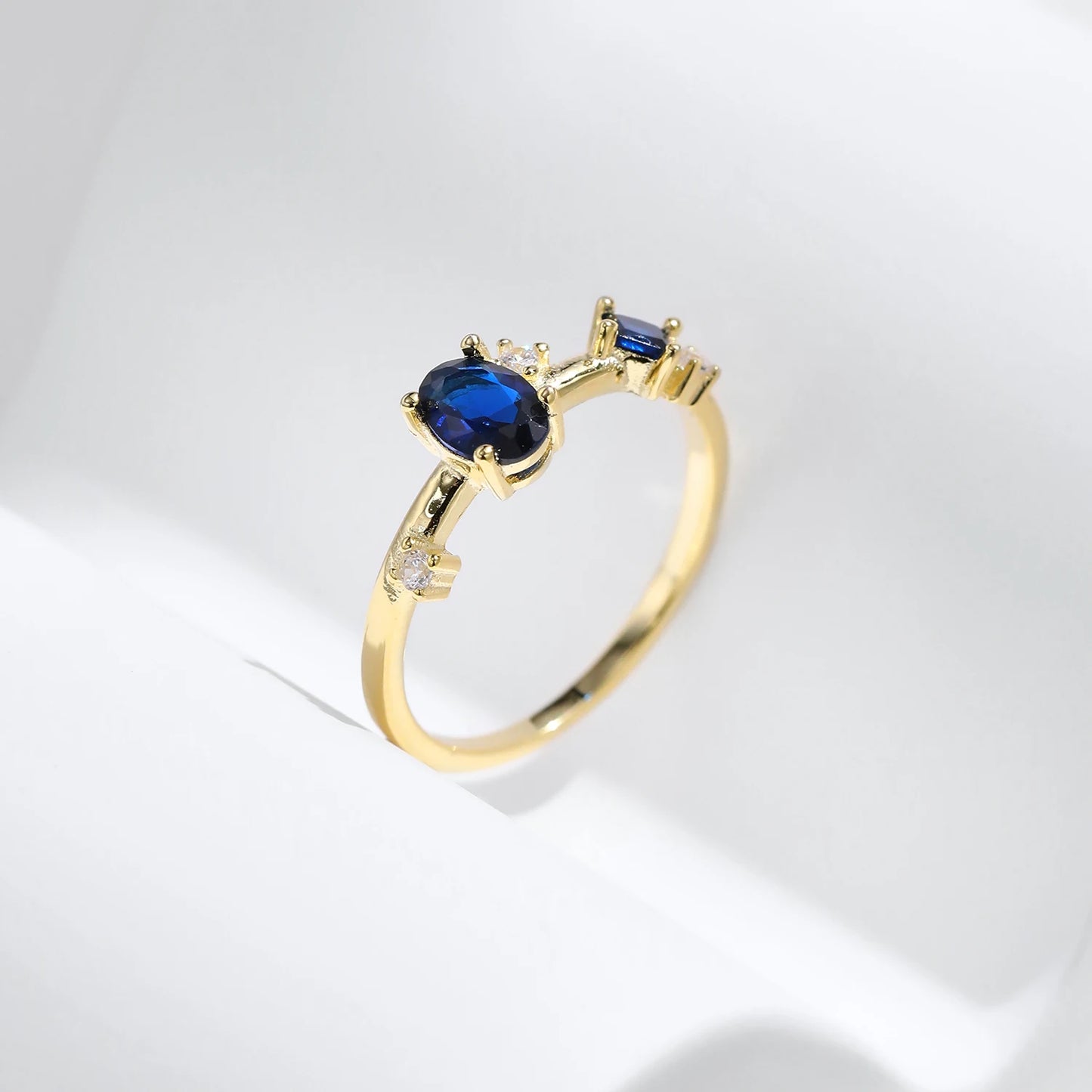 Gold-plated ring with deep blue oval and round stones set in a modern scattered design
