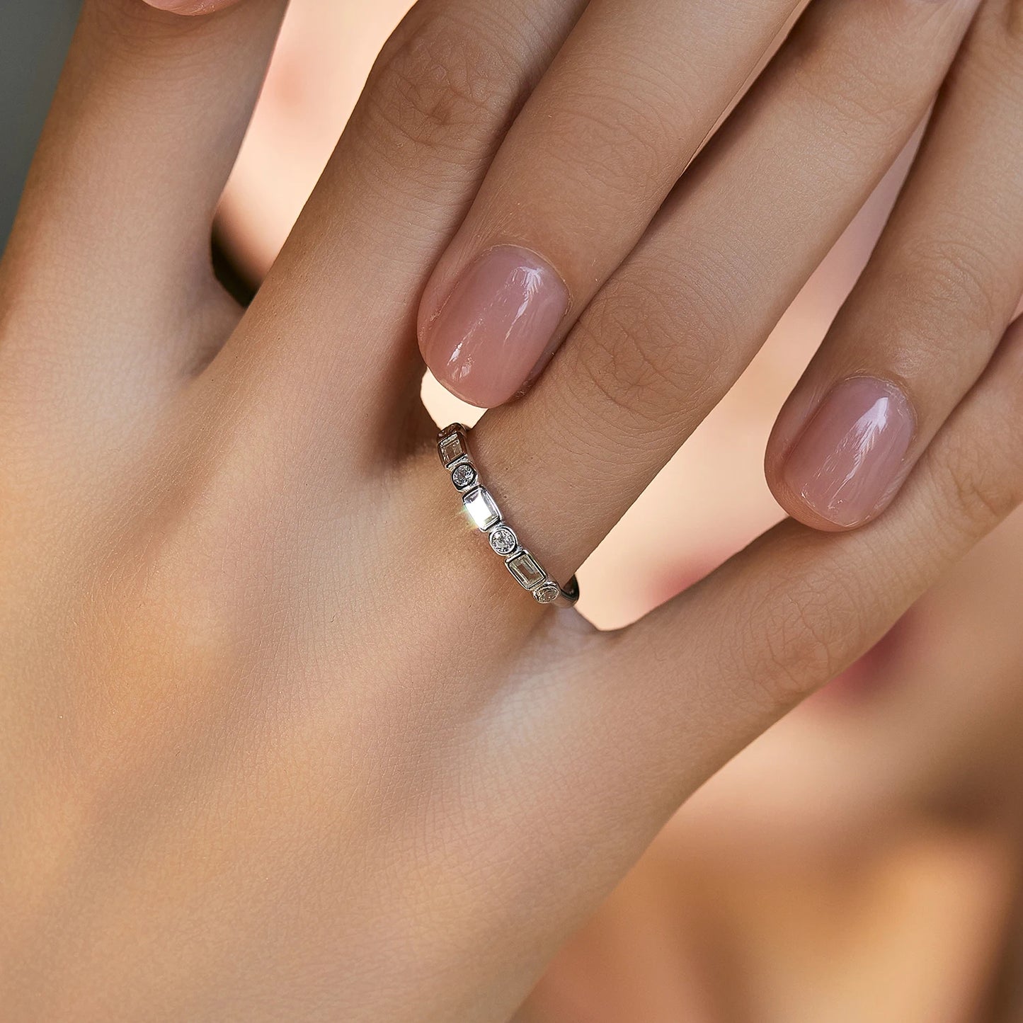 Silver ring featuring alternating round and baguette-cut white stones in a half-band setting.