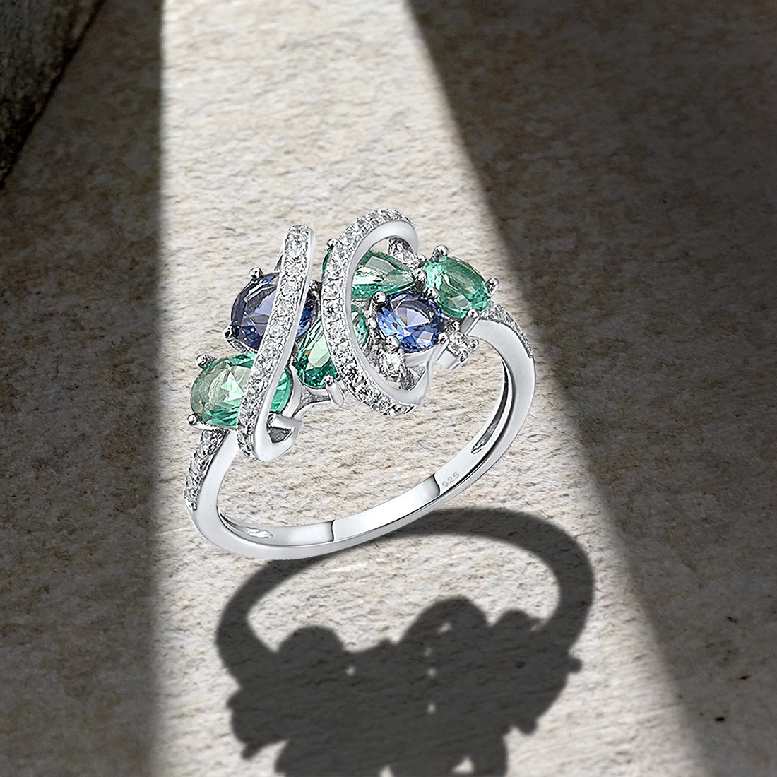 Sterling silver ring with swirling bands of pavé stones and clustered green and blue round-cut gemstones