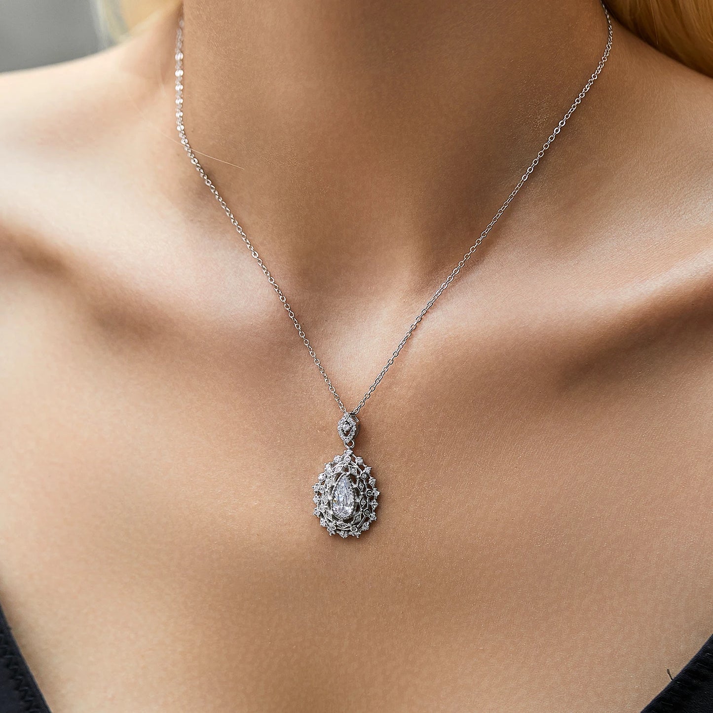 Ornate silver necklace with an intricate teardrop pendant, featuring a central pear-cut white gemstone, part of the Bianco Nero collection.