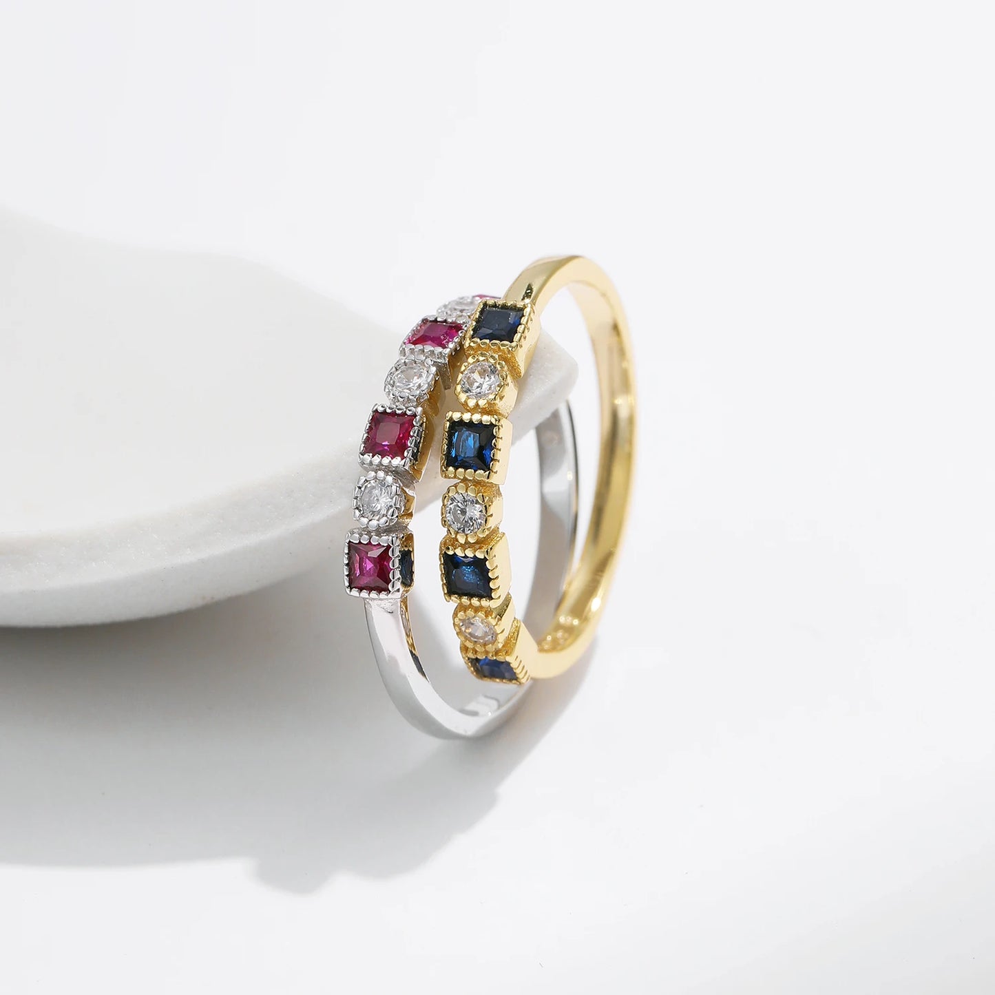 Sterling silver ring with alternating square-cut red stones and round clear stones in a linear setting.