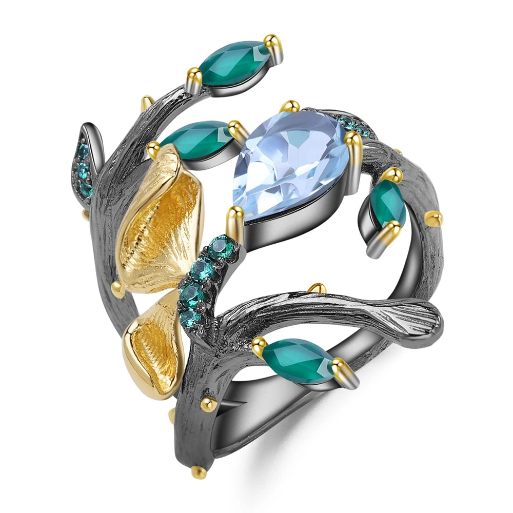 Black branch-style ring with sky-blue and green stones, gold leaves, and textured detailing