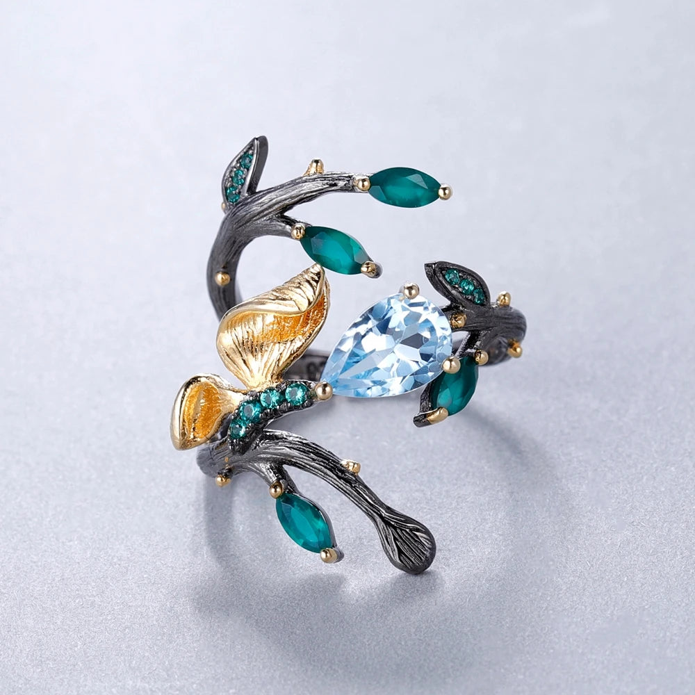 Black branch-style ring with sky-blue and green stones, gold leaves, and textured detailing