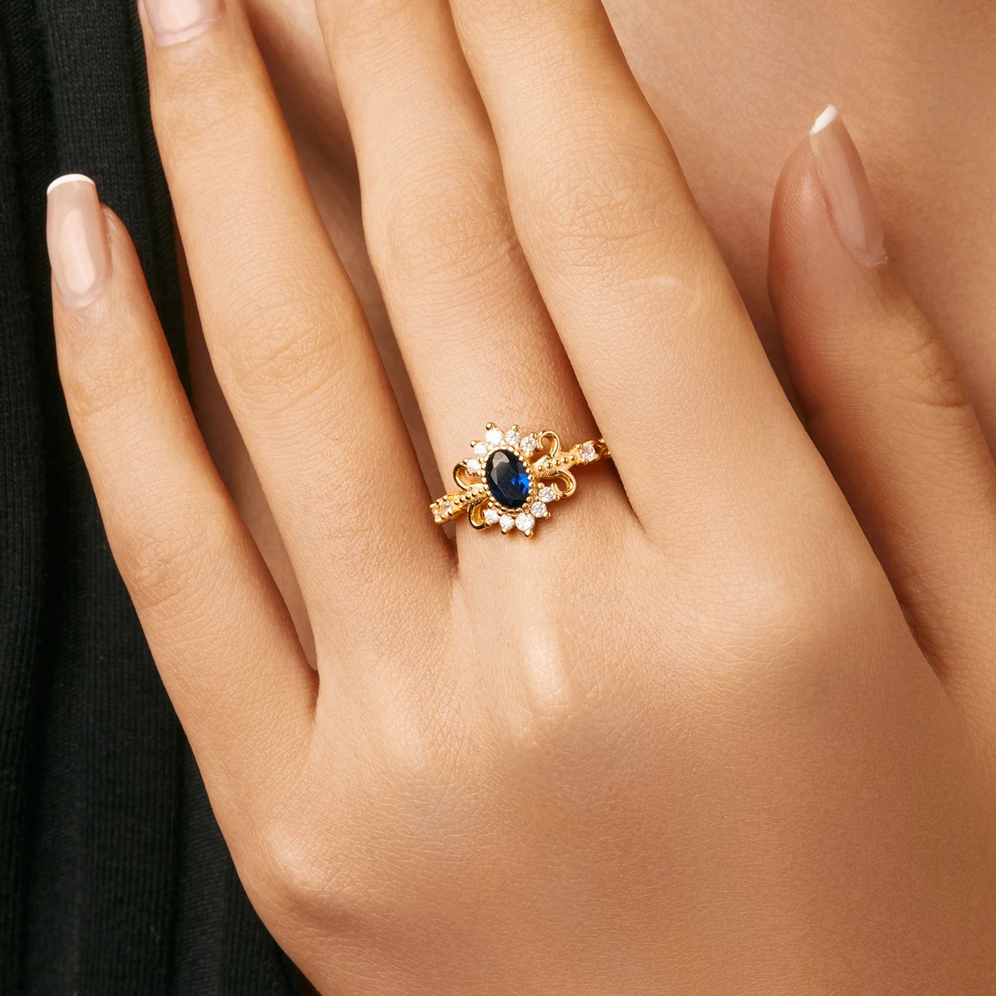 Vintage-style gold ring with deep blue oval center stone surrounded by clear accent stones