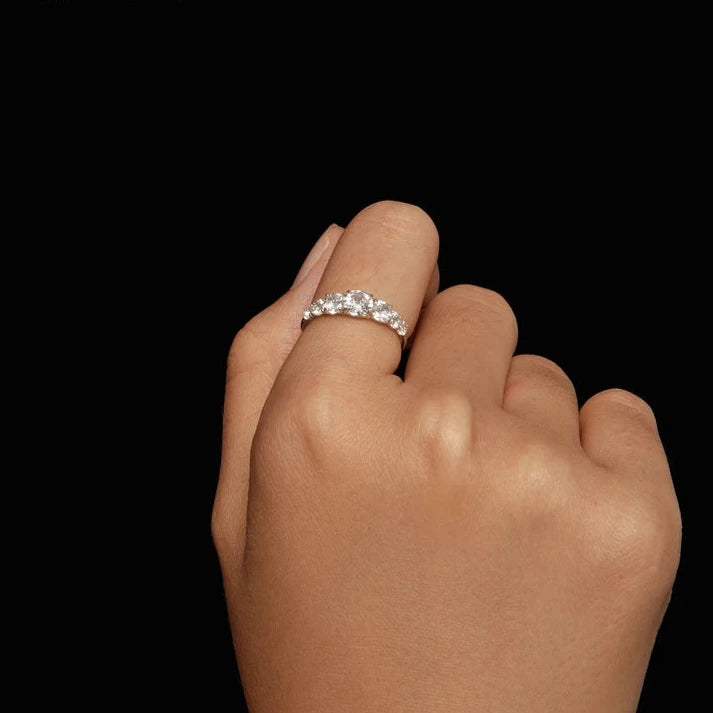 Silver band ring adorned with a sequence of round brilliant-cut stones, creating a continuous sparkling design.
