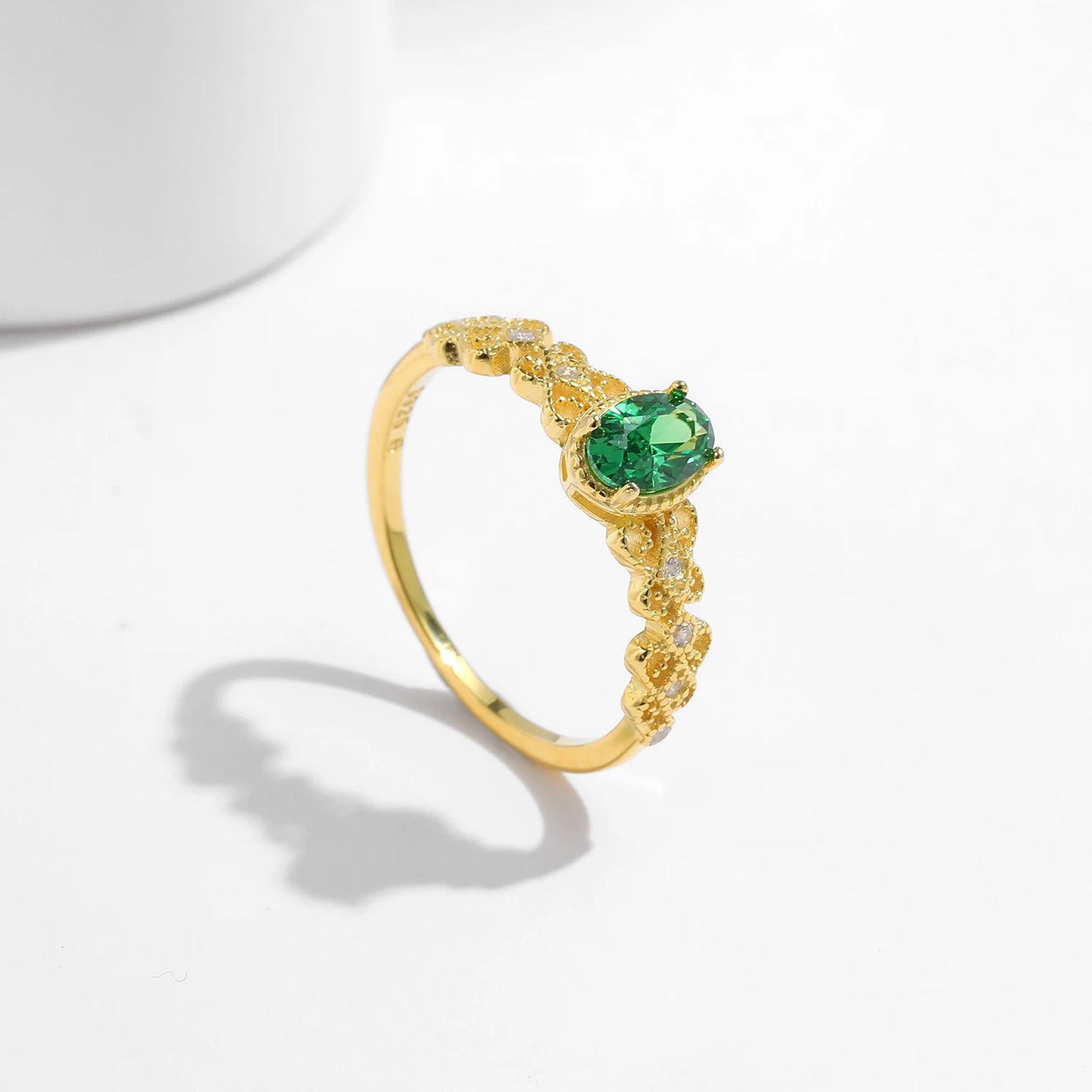 Gold-plated silver ring with a green oval gemstone and delicate diamond-accented detailing.