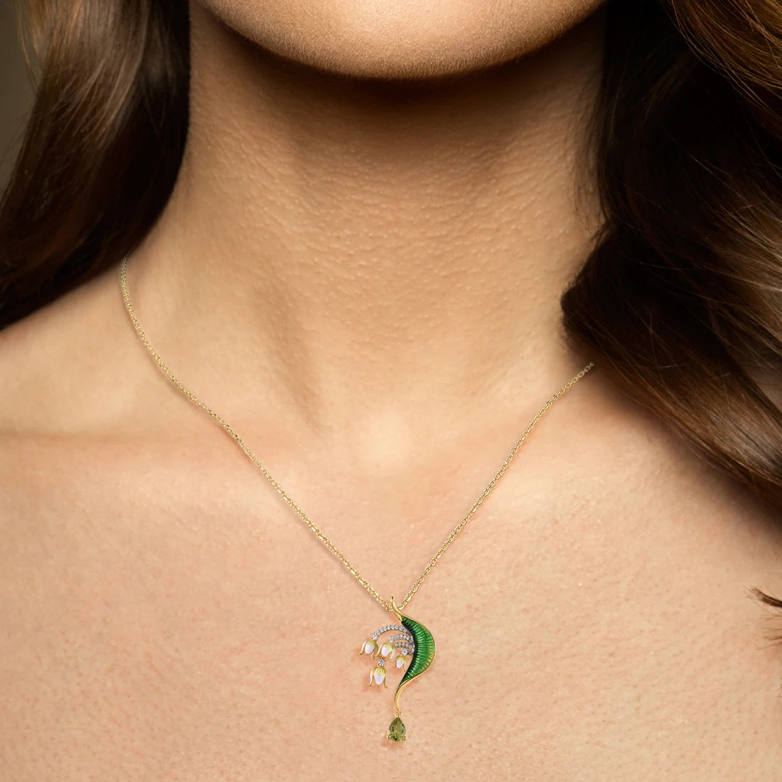 Gold brooch with green enamel leaf, white and pink floral drops, and teardrop green gemstone