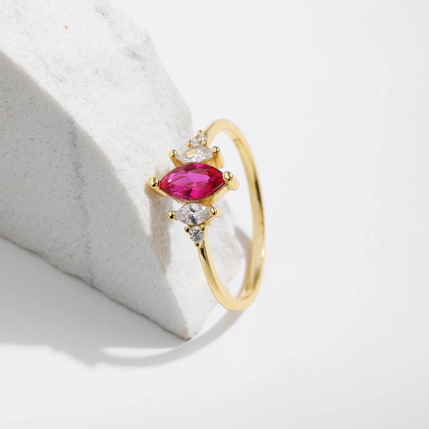 Gold-plated ring with marquise-cut ruby-pink stone and clear side accents