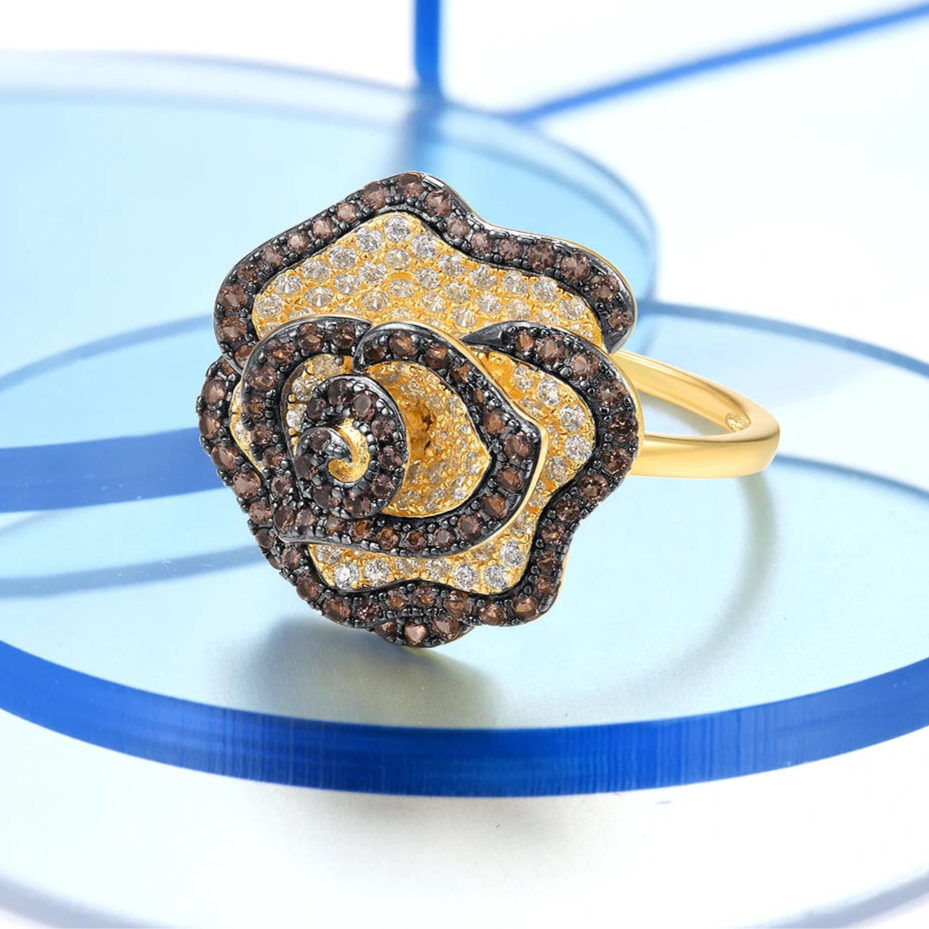 Gold ring shaped like a blooming rose with pavé white and brown stones.