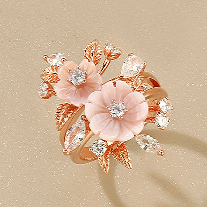 Begonia ring with carved peach-toned flowers, white stones, and rose gold leaves in an intricate botanical design.