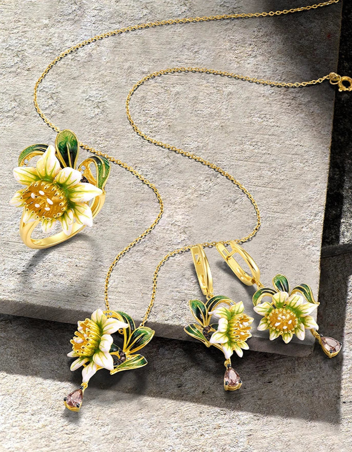Gold floral jewelry set with white and green enamel petals, gold detailing, and brown teardrop stones