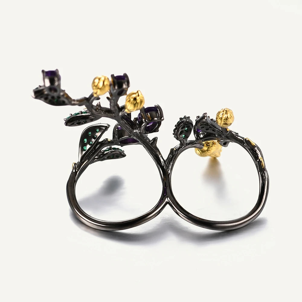 Double-finger black ring shaped like a flowering branch with purple, green, and gold detailing