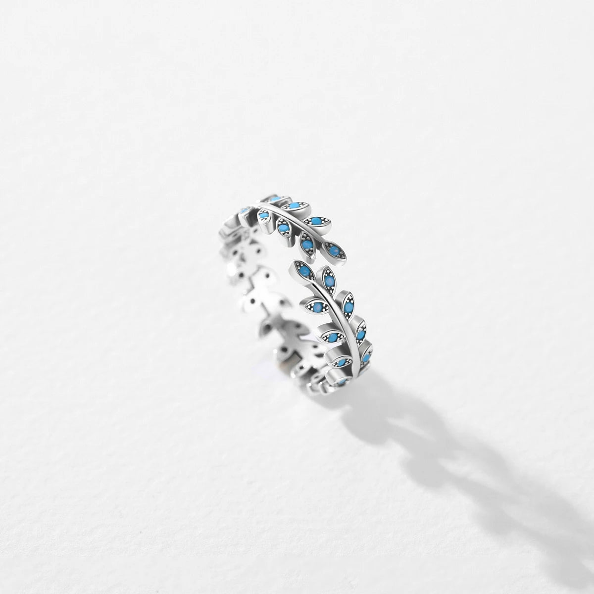 Silver ring shaped like a delicate laurel branch with light turquoise enamel accents on the leaves