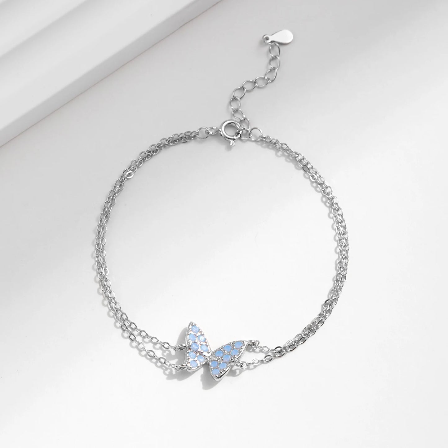 Delicate silver bracelet with a central opal butterfly charm and fine double chain