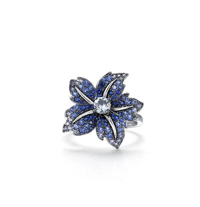 Silver ring shaped like a flower, with deep blue pavé stones and a clear central gem