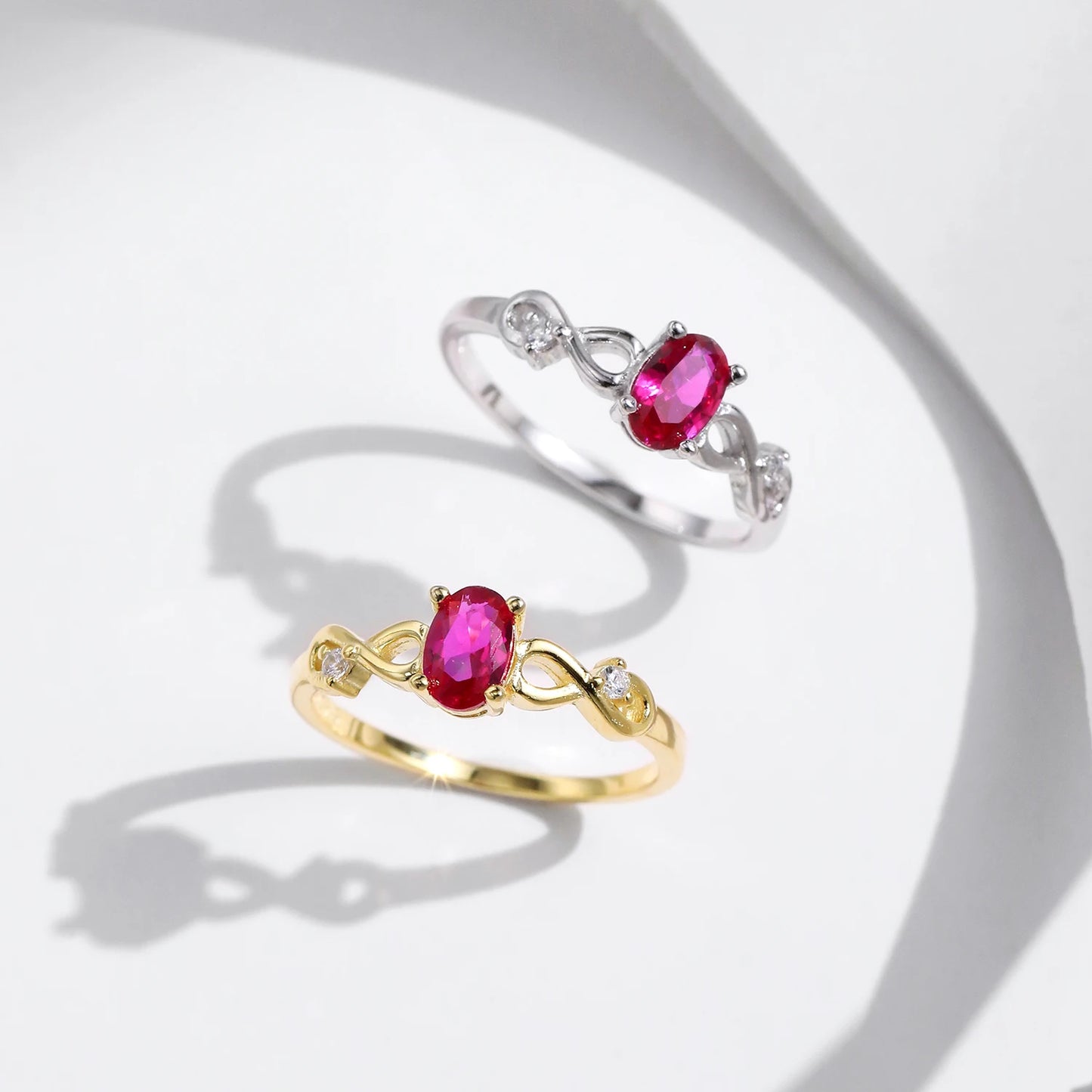 Gold-plated ring with an oval pink gemstone and twisted infinity-style band
