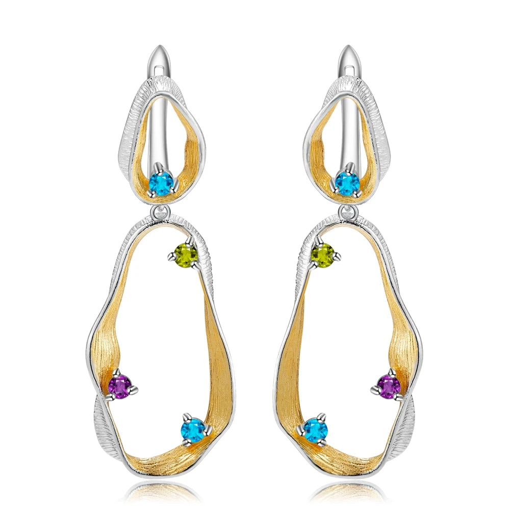 Dangling earrings with flowing gold and silver forms set with turquoise-colored stones