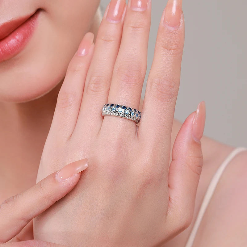 Sterling silver eternity band with alternating light and dark blue stones in a woven design