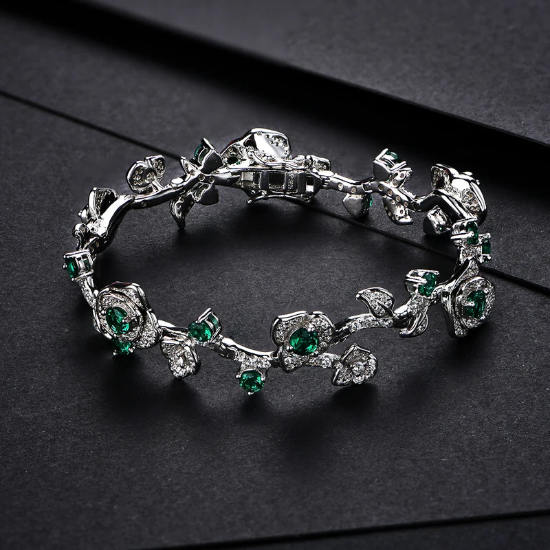 Silver bracelet with green stones and leafy vine design