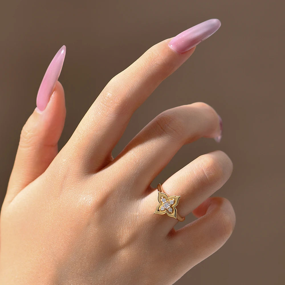 Hand wearing a gold ring with a diamond design on a brown background