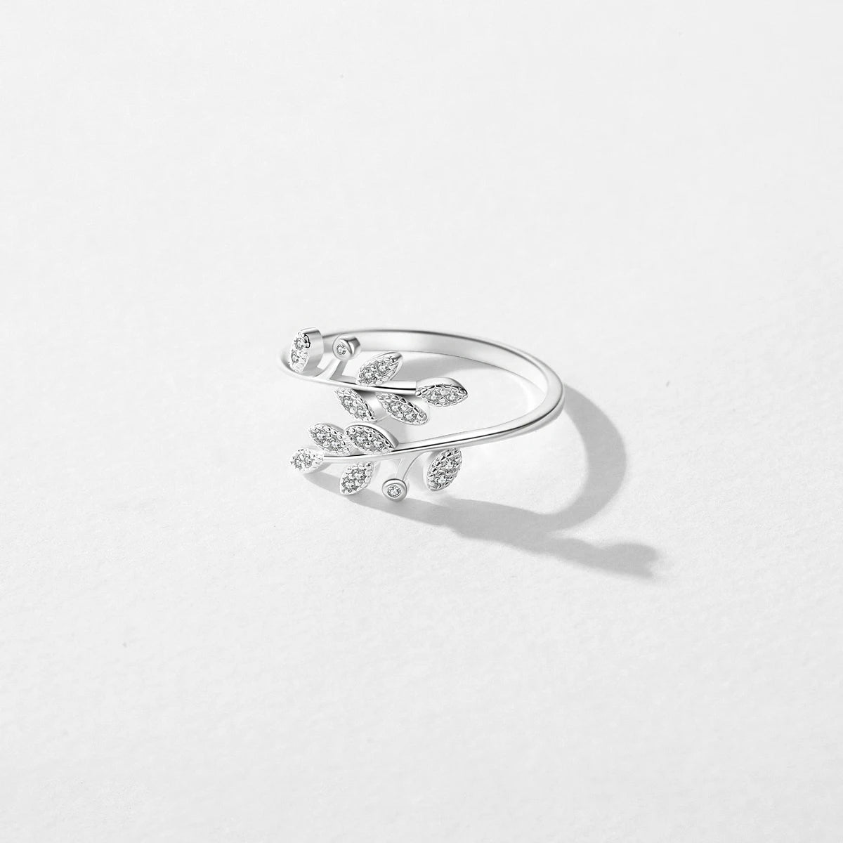 Silver ring designed with two curved branches, each adorned with pavé-set leaf shapes and tiny round white stones.