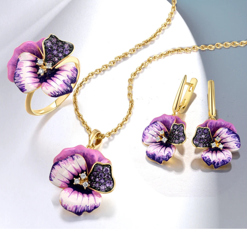 Gold jewelry set with violet enamel pansy flowers and pavé purple stones, including earrings, pendant, and matching ring