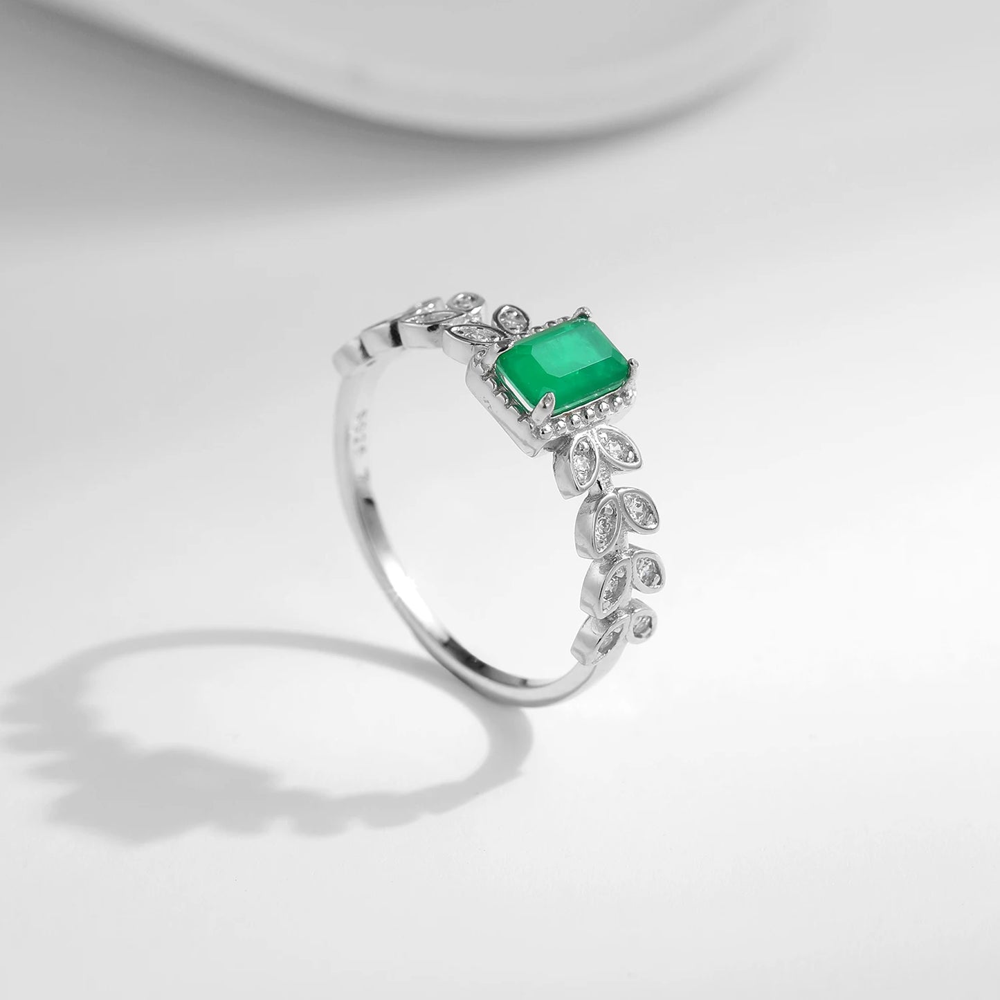 Rectangular green gemstone ring with delicate leaf-inspired silver accents and small clear stones.
