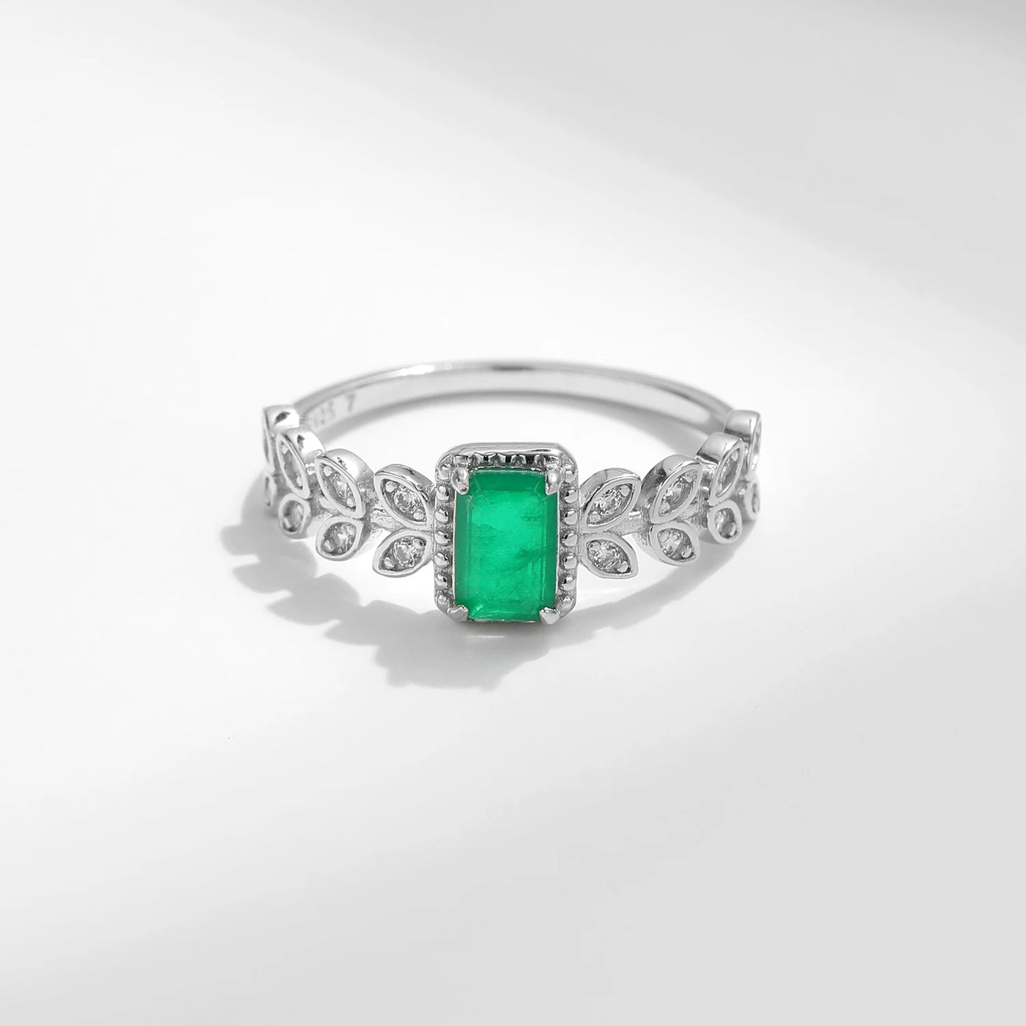 Rectangular green gemstone ring with delicate leaf-inspired silver accents and small clear stones.