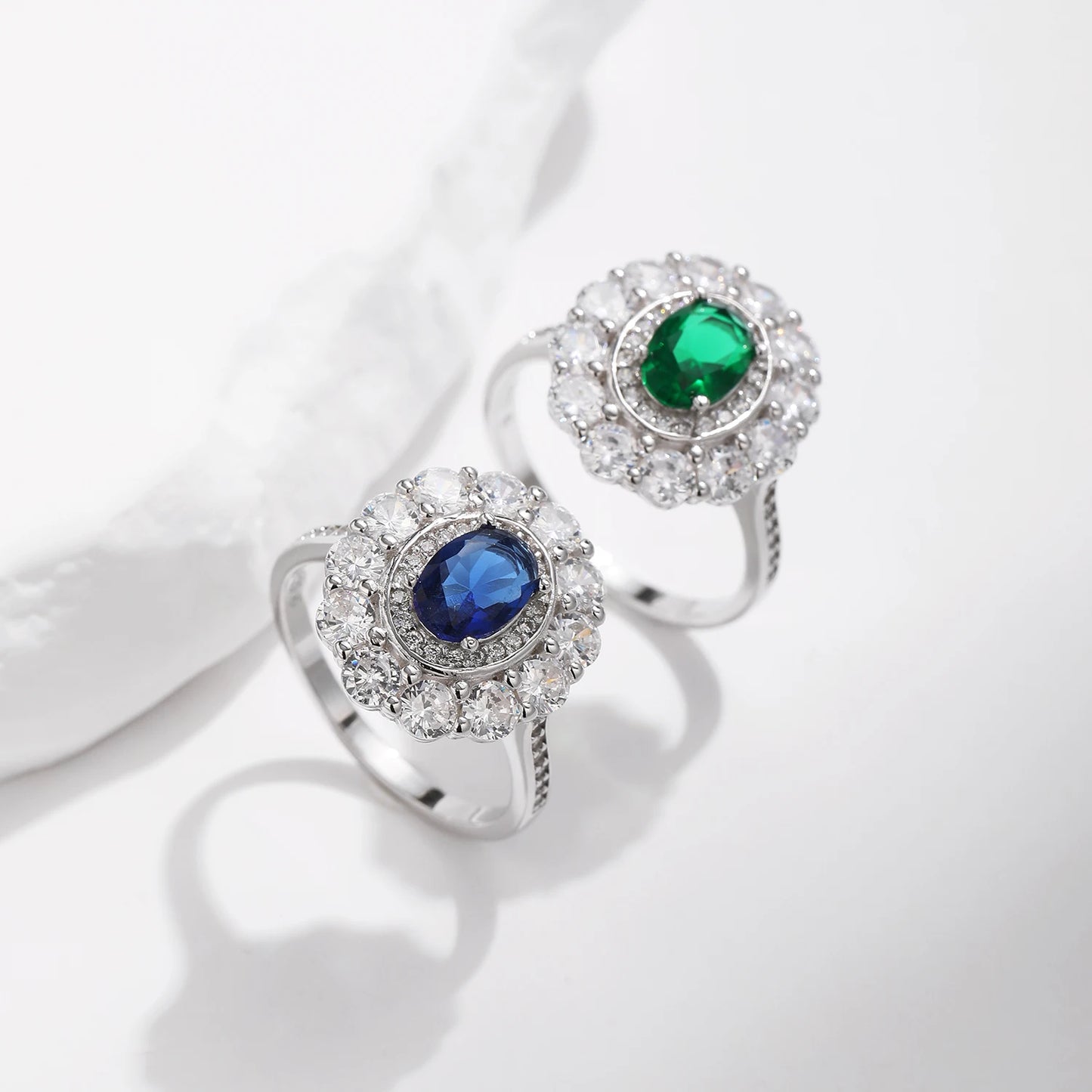 Silver ring with an oval deep blue or green stone surrounded by two halos of clear zirconia stones