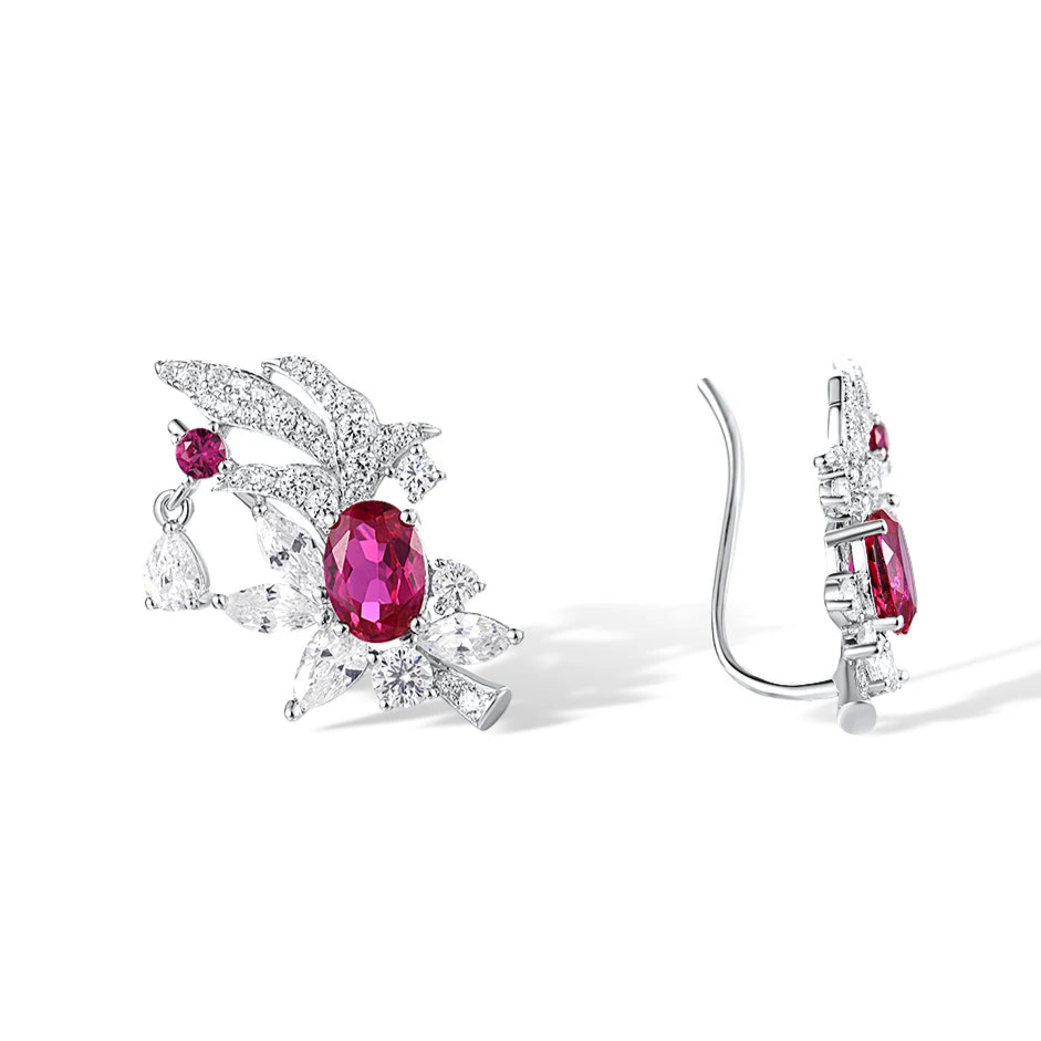Birmania earrings featuring vivid oval ruby-colored stones surrounded by white crystal floral accents and pear-cut dangles.