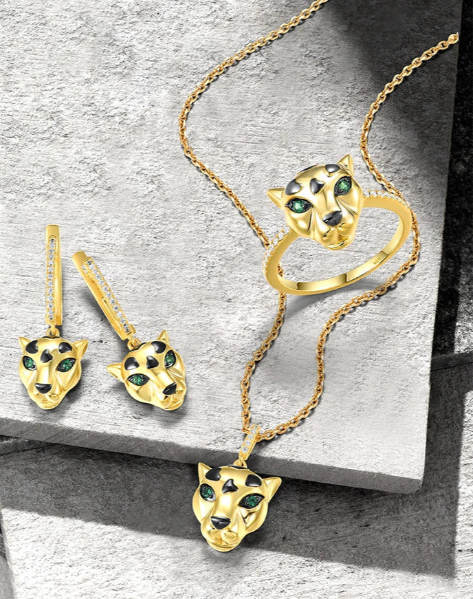 Gold jewelry set featuring panther heads with black spots and green eyes, including earrings, pendant, and ring